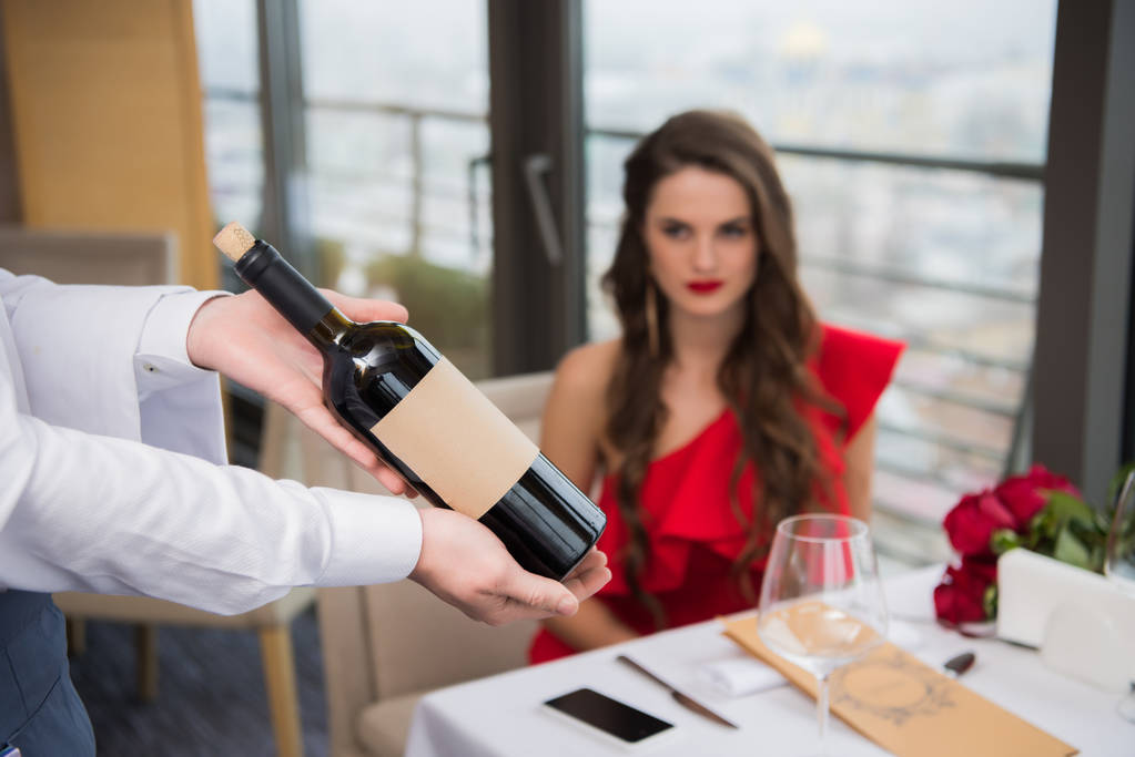 selektiver Fokus des Kellners, der eine Flasche Wein im Restaurant hält - Foto, Bild
