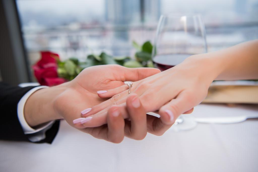 bijgesneden schot van vriendje verloofden hand houden tijdens romantische datum in restaurant - Foto, afbeelding