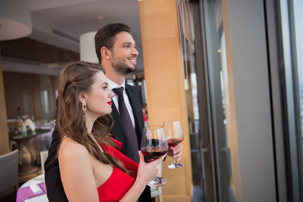 ζευγάρι με ποτήρια κόκκινο κρασί γιορτάζει την ημέρα του Αγίου Βαλεντίνου στο εστιατόριο - Φωτογραφία, εικόνα