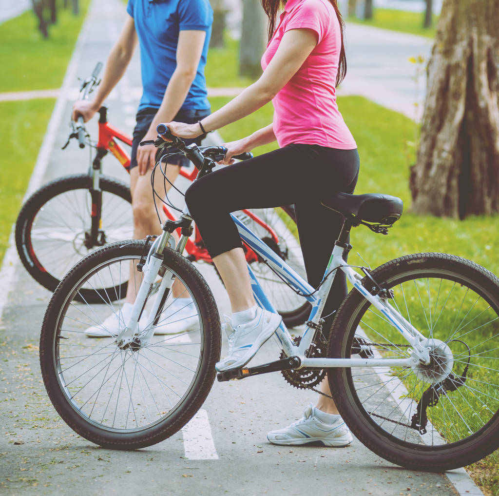 Joven pareja caucásica ciclismo en carril bici verde en día soleado
 - Foto, imagen