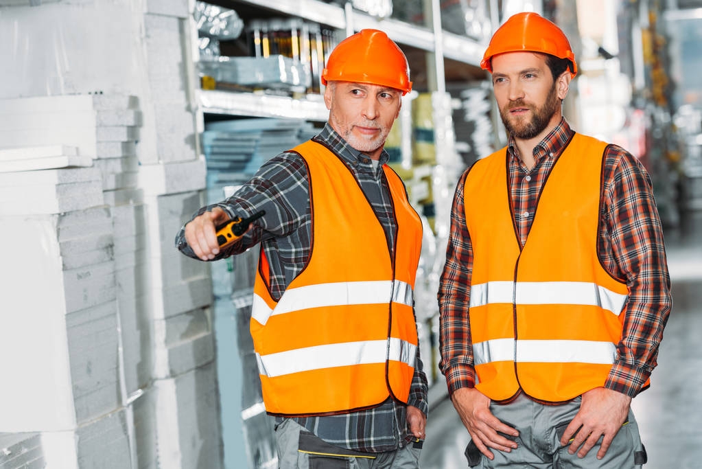 deux travailleurs masculins tenant un talkie-walkie dans un entrepôt
 - Photo, image
