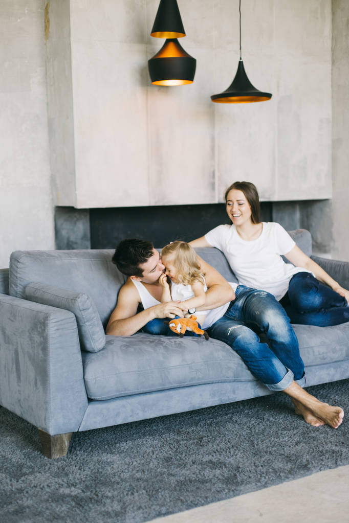 młode piękne rodziny spędzać czas razem na niebieski kanapie w domu - Zdjęcie, obraz
