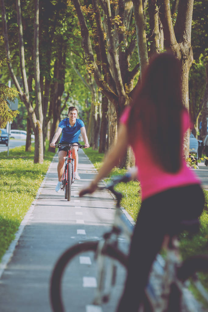 晴れた日に緑の自転車レーンにサイクリング若い白人カップル - 写真・画像
