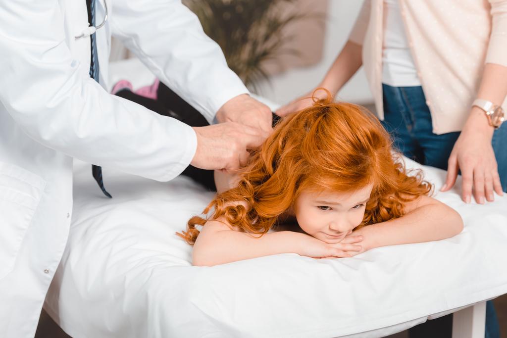 Μερική άποψη της γιατρός εξετάζει το χαριτωμένο μικρό κορίτσι κατά τη λήψη στην κλινική - Φωτογραφία, εικόνα