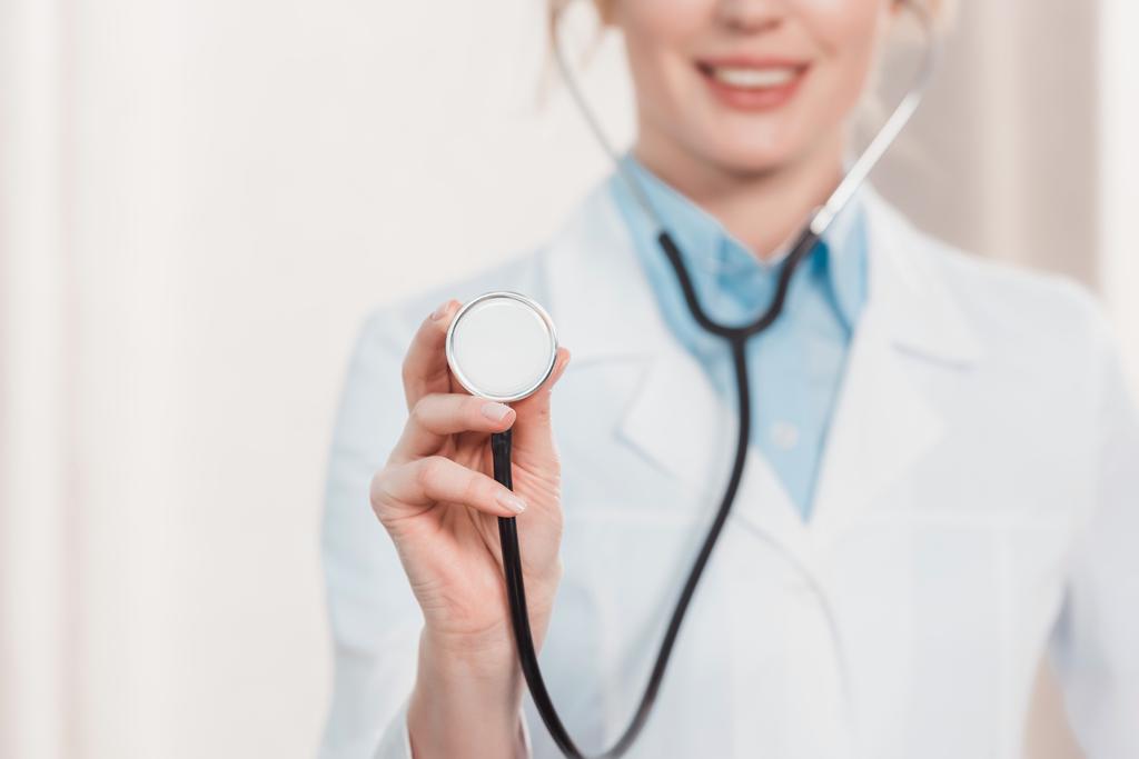 částečný pohled s úsměvem lékař zobrazeno stetoskop v ruce - Fotografie, Obrázek