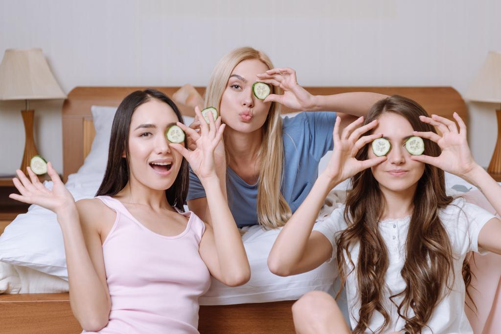 three beautiful multicultural girls covering eyes with cucumber pieces  - Photo, Image