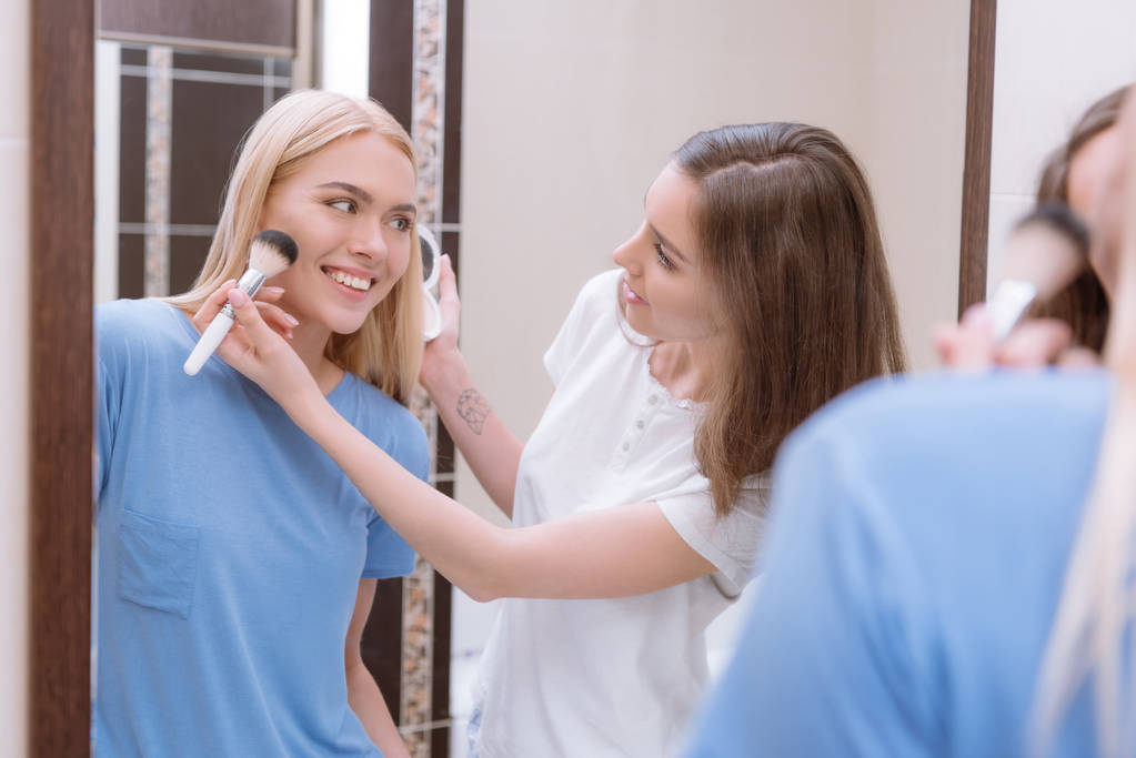 menina aplicando pó de fundação com escova de maquiagem no rosto amigos
  - Foto, Imagem
