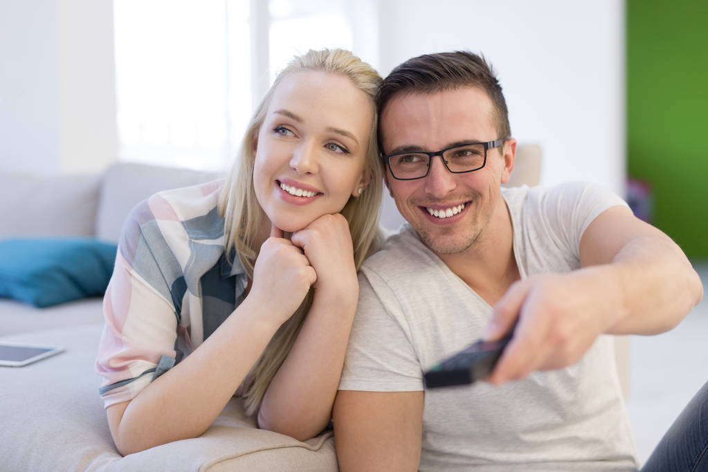 Giovane coppia sul divano a guardare la televisione
 - Foto, immagini