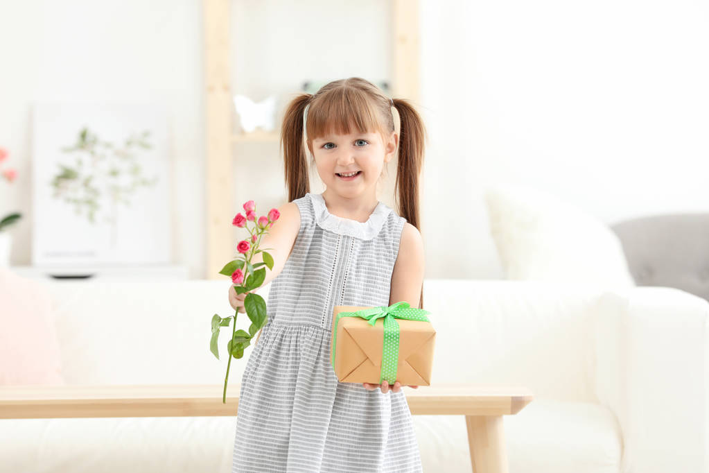 Bambina che tiene la scatola regalo e il fiore per la festa della mamma a casa
 - Foto, immagini