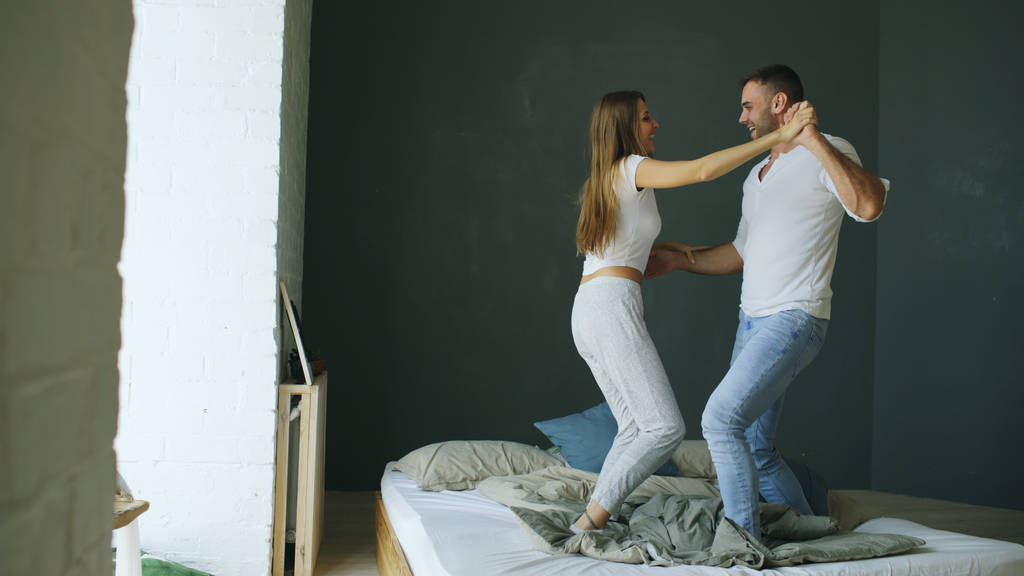 Jeune beau et aimant couple dansant sur le lit le matin
 - Photo, image