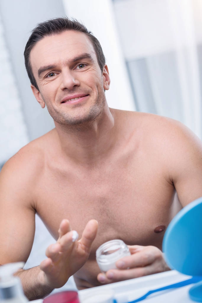 Hombre guapo desnudo hidratante con crema facial
 - Foto, Imagen