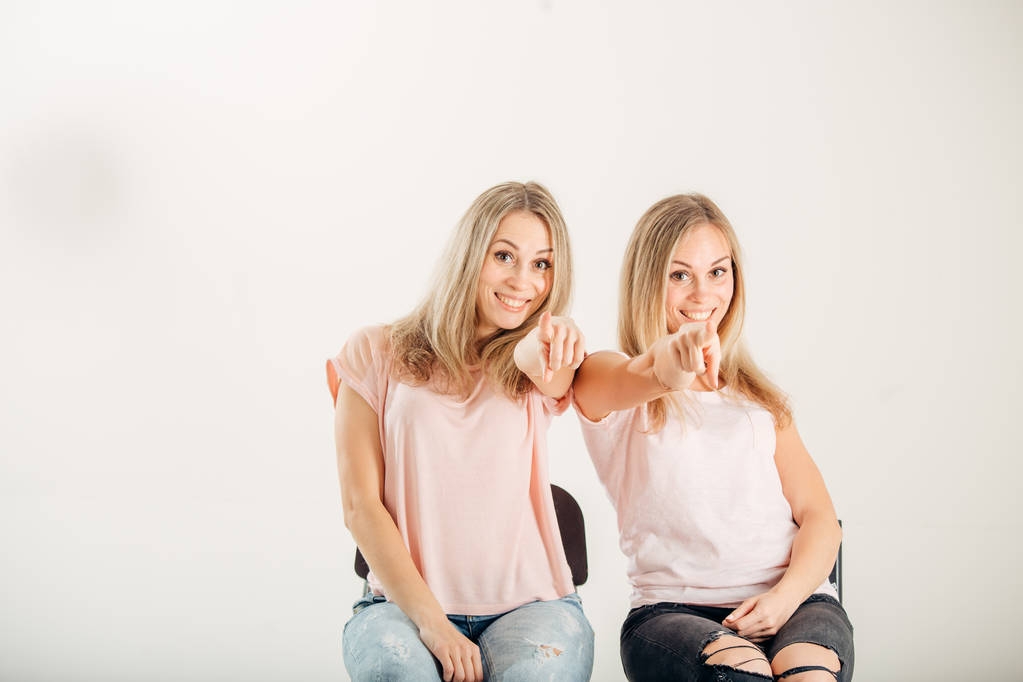 Twee attrative zusters tweelingen wijzen op witte achtergrond - Foto, afbeelding