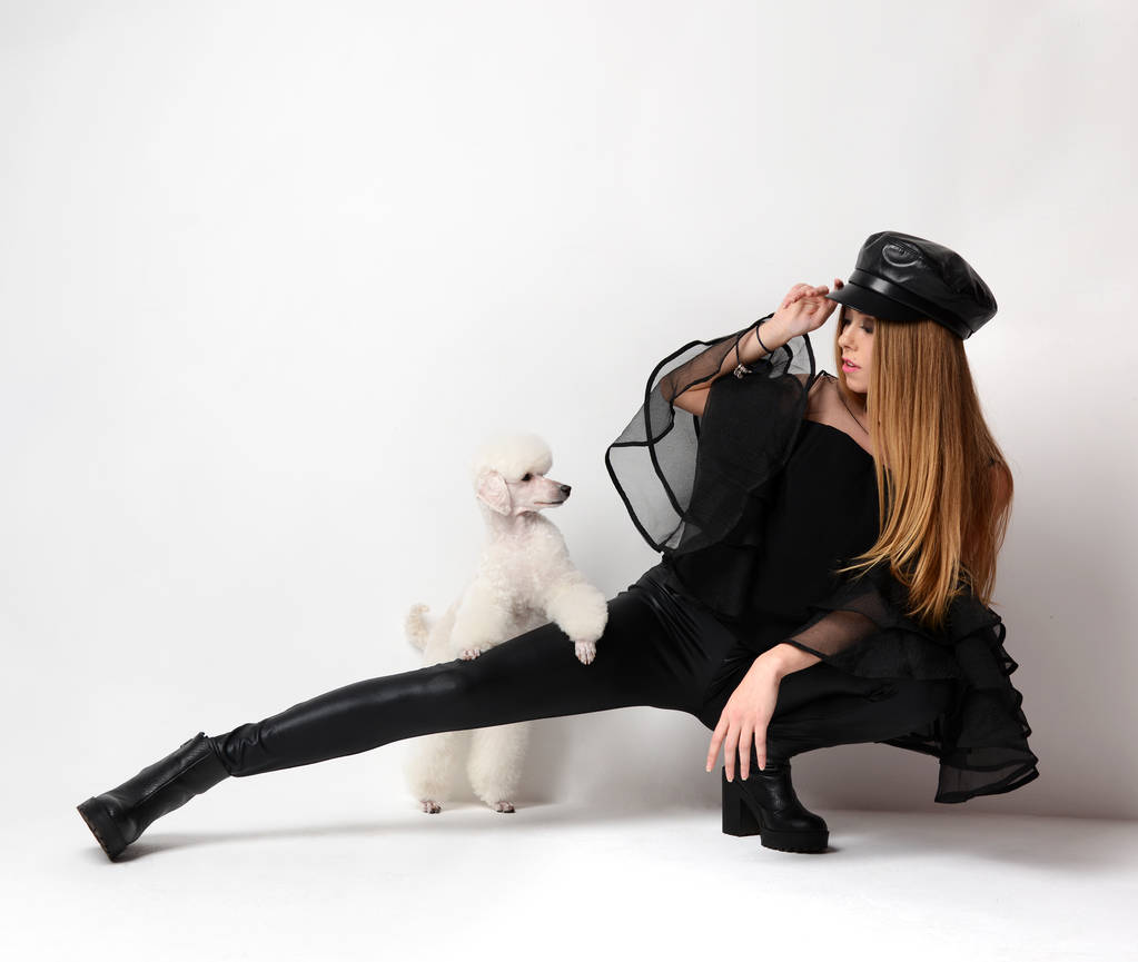 Jovem mulher glamour moda em blusa preta e chapéu com cão poodle branco
  - Foto, Imagem