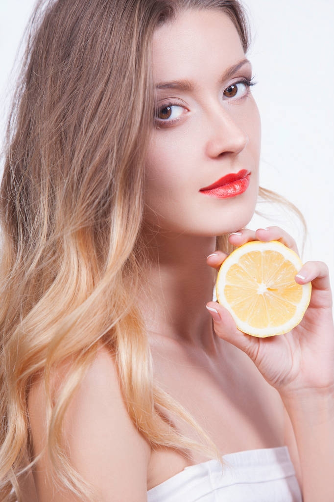 Portrait studio de jeune femme ludique avec des lèvres rouges et moitié citron dans les mains sur fond gris
 - Photo, image