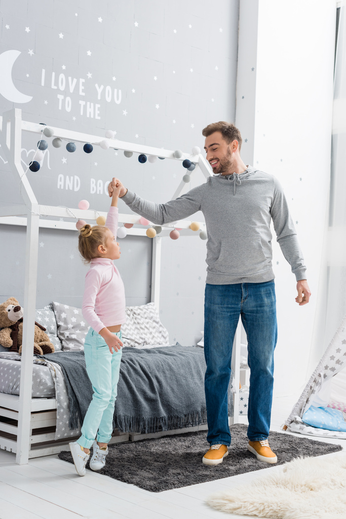 onnellinen nuori isä tanssii tyttären kanssa lapsi makuuhuoneessa
 - Valokuva, kuva
