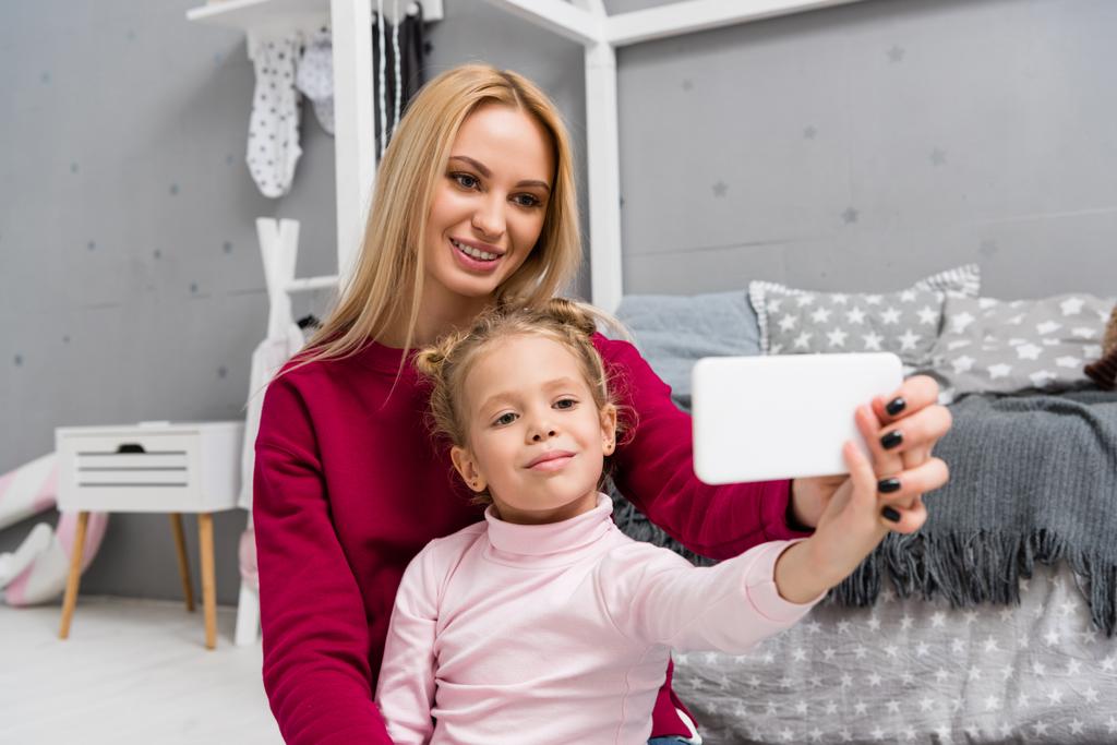 mother and daughter taking selfie in kid bedroom - Photo, Image