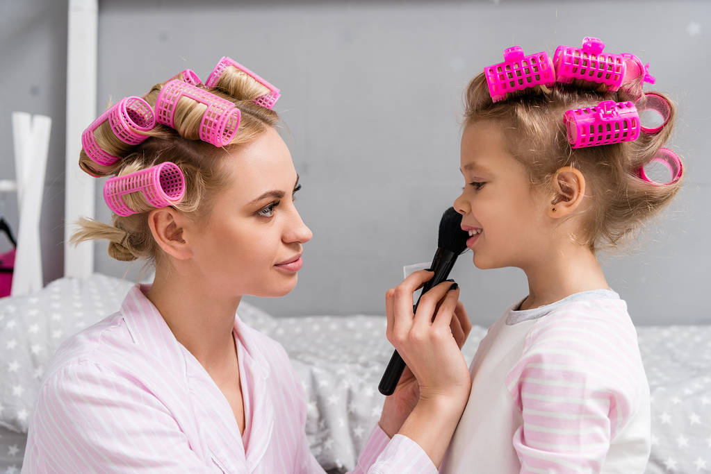 Mladá krásná matka a dcera s natáčky dělá make-up - Fotografie, Obrázek