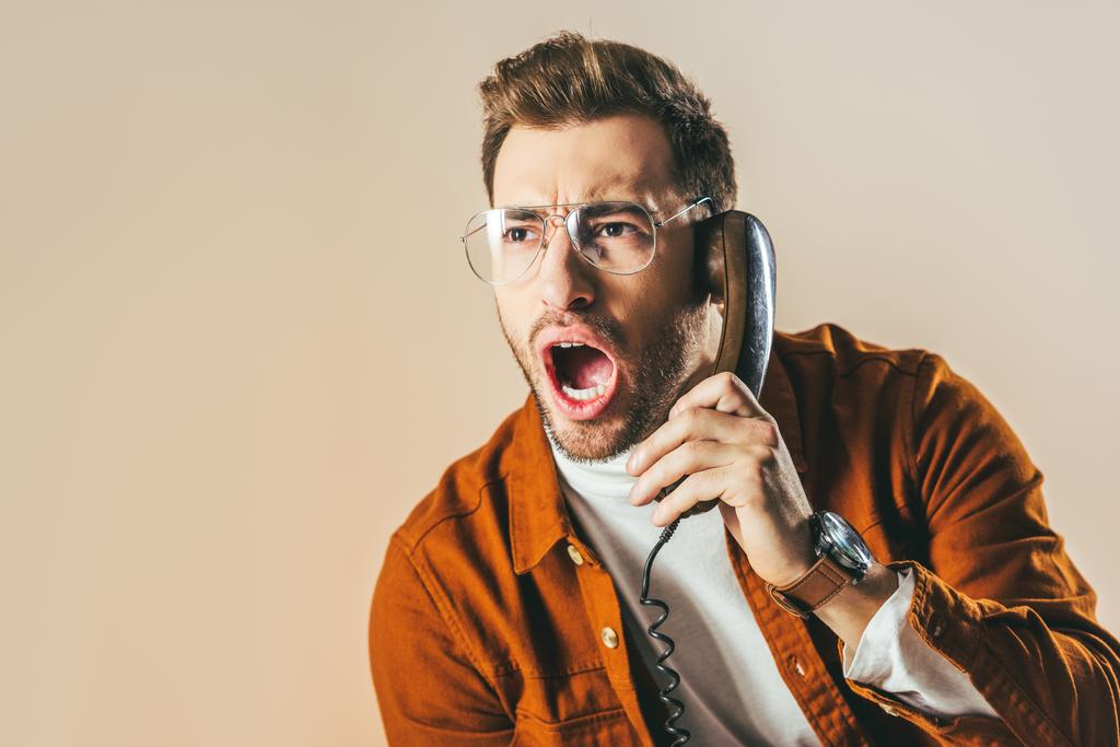 retrato de hombre elegante gritando mientras habla por teléfono aislado en beige
 - Foto, imagen