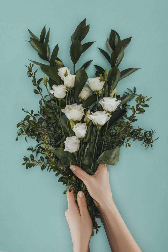 bijgesneden afbeelding van vrouwelijke handen met boeket met eustoma bloemen geïsoleerd op groen - Foto, afbeelding