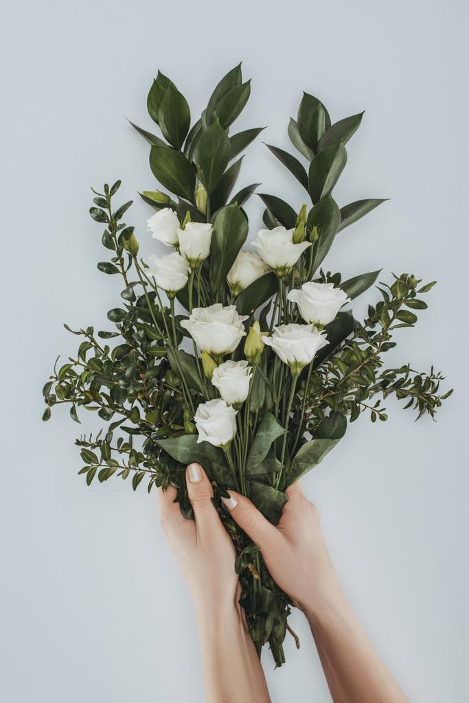 bijgesneden afbeelding van vrouwelijke handen met boeket met eustoma bloemen geïsoleerd op grijs - Foto, afbeelding