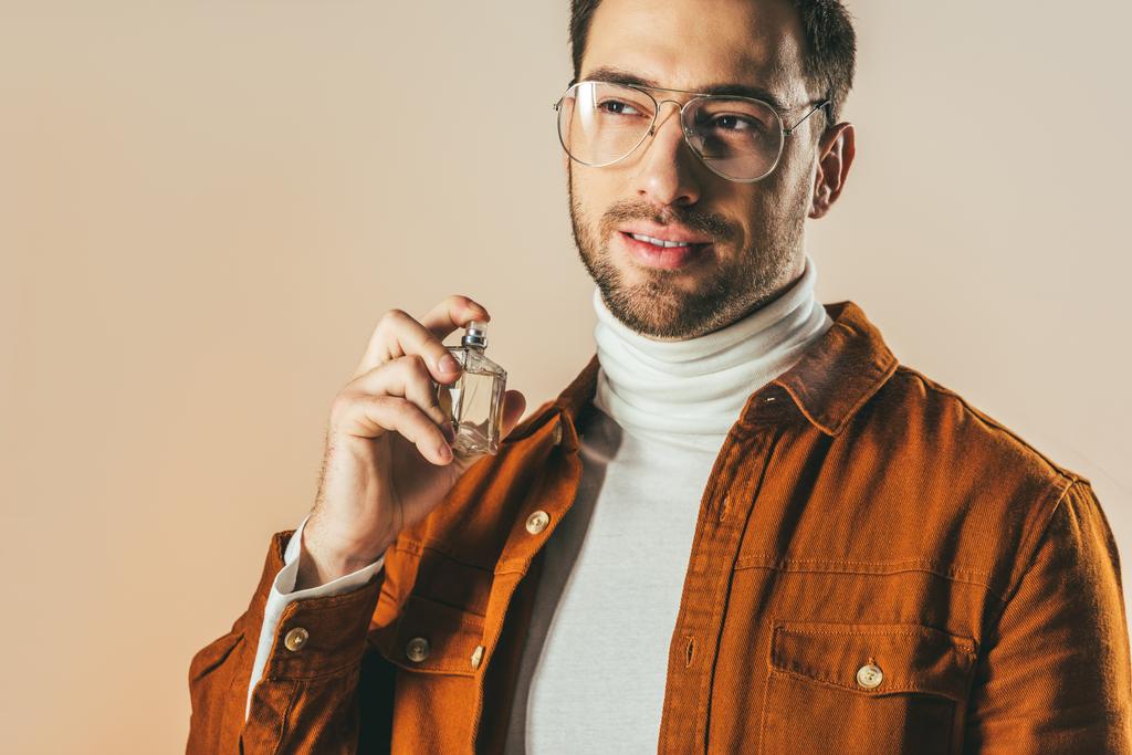portrait de jeune homme élégant appliquant parfum isolé sur beige
 - Photo, image