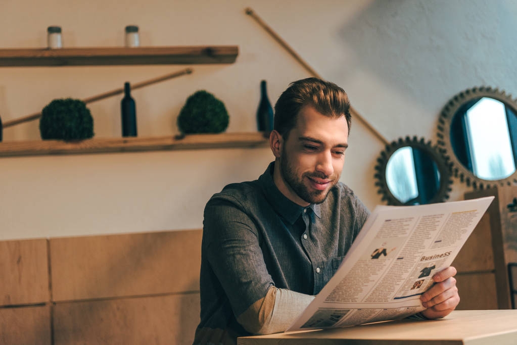 portret uśmiechający się biznesmen czytanie gazety przy stoliku w kawiarni - Zdjęcie, obraz