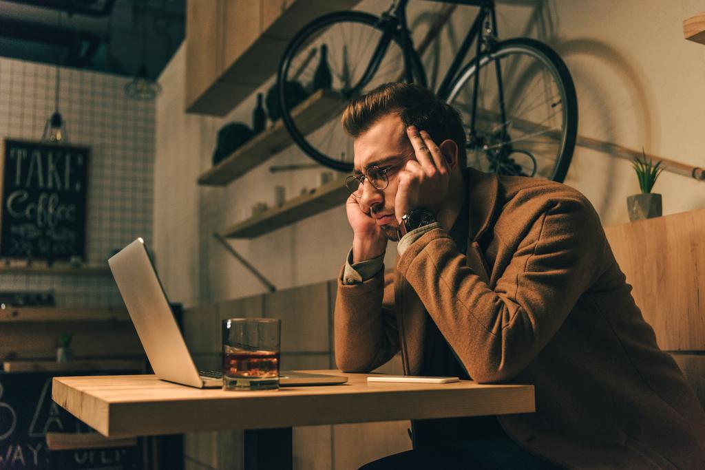 стрессовый мужчина смотрит на экран ноутбука во время работы в кафе
 - Фото, изображение