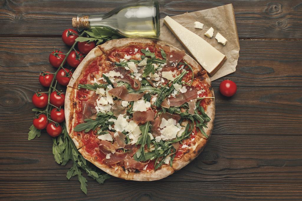 vlakke leggen met Italiaanse pizza en diverse ingrediënten op houten tafelblad - Foto, afbeelding