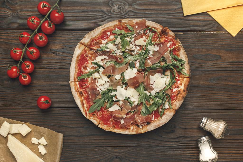 tasainen makasi kotitekoinen italialainen pizza, oliiviöljy, kirsikkatomaatit ja juusto puupinnalla
 - Valokuva, kuva