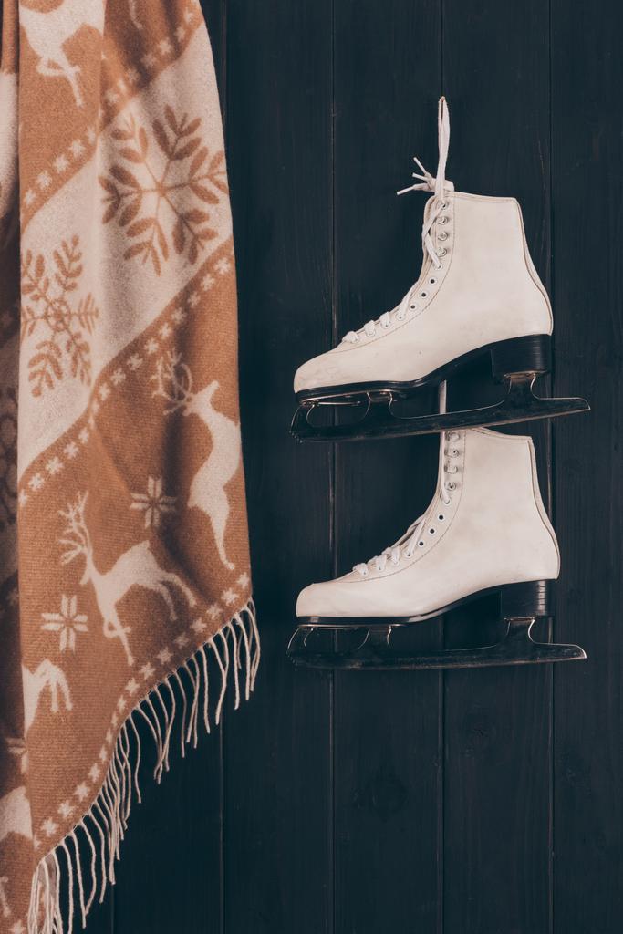 пара білих ковзанів і шарфів, що висять на стіні
 - Фото, зображення