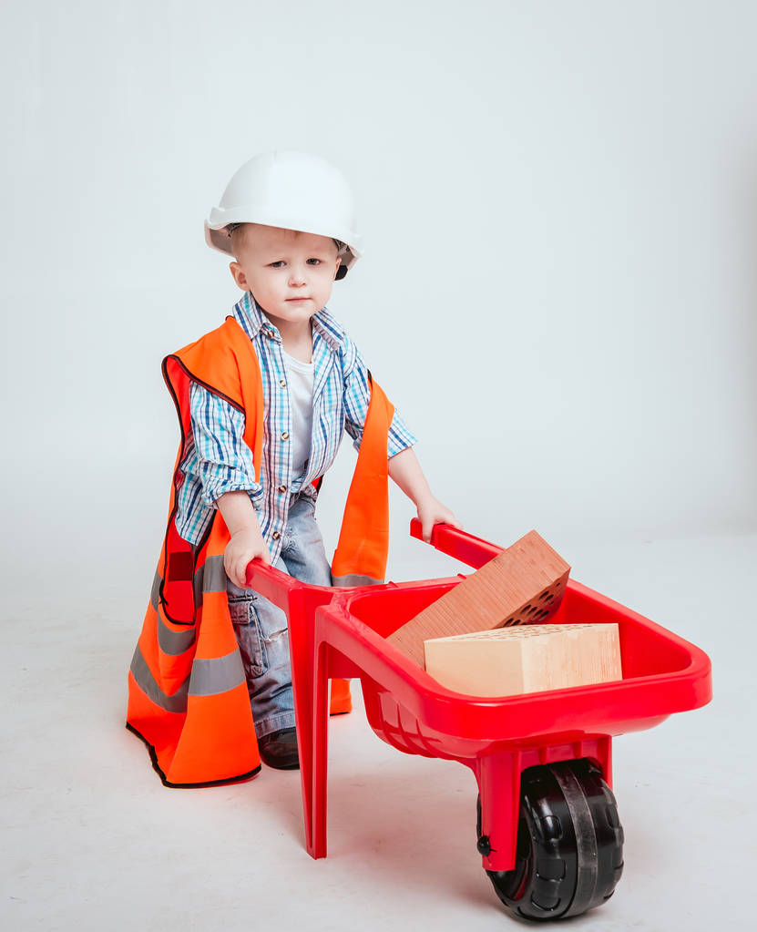 Маленький хлопчик з візком на білому тлі. Будівництво, ремонт, інтер'єр
. - Фото, зображення