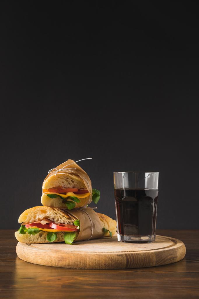 δύο σάντουιτς σε κάθε άλλο και γυαλί κόλα σε ξύλο κοπής  - Φωτογραφία, εικόνα