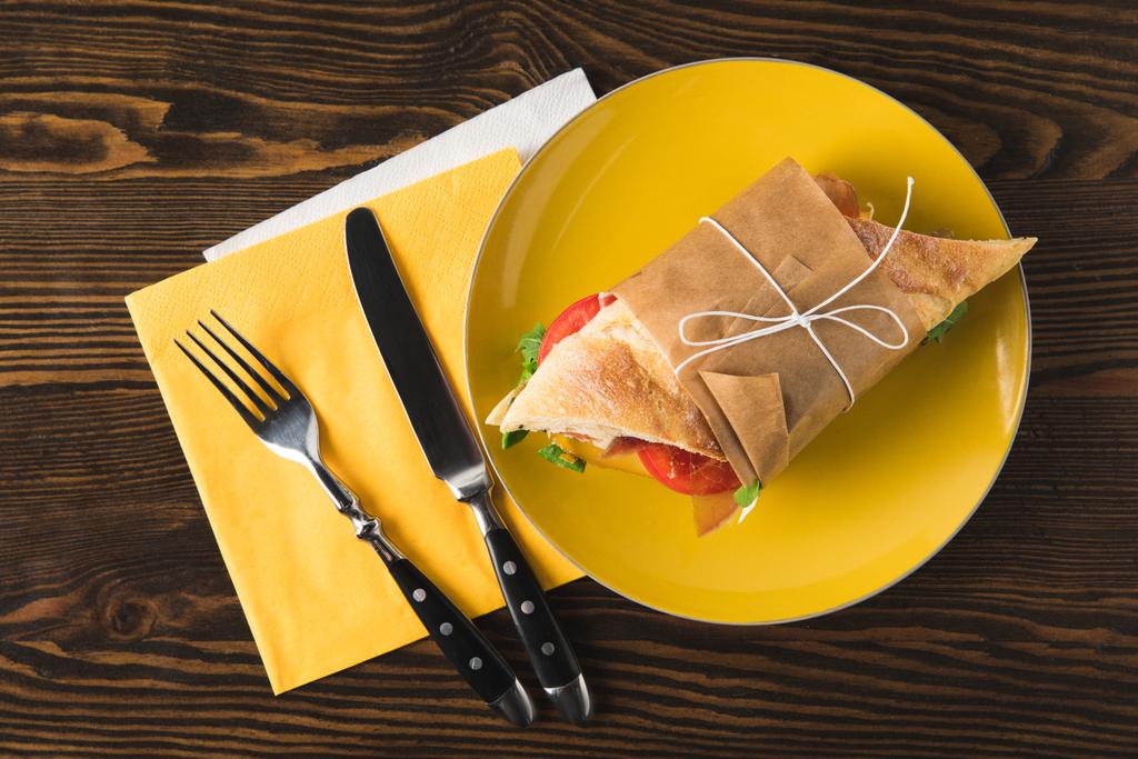 top view of panini on yellow plate with fork and knife - Photo, Image