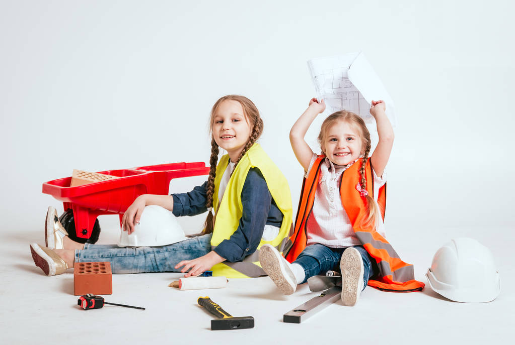 Deux petites filles gaies avec des tresses jouant dans la réparation ou la construction sur blanc
 - Photo, image
