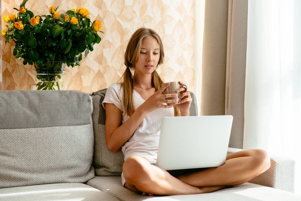 Жінка дивиться серіали на ноутбук на дивані вдома
 - Фото, зображення