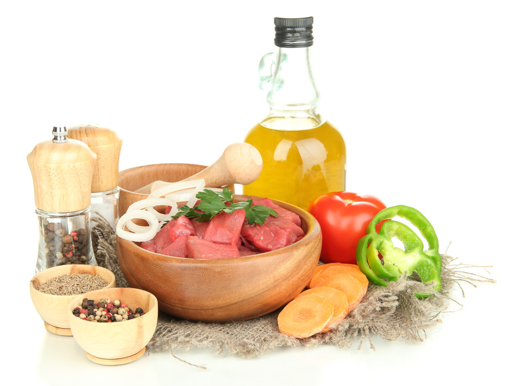 Carne de res cruda en un tazón con hierbas, especias y aceite de cocina aislado en blanco
 - Foto, Imagen