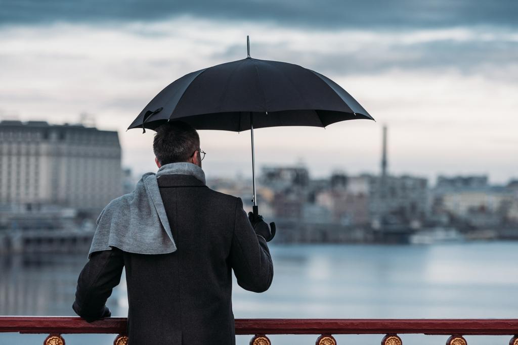 back view of lonely man with umbrella standing on bridge - Photo, Image