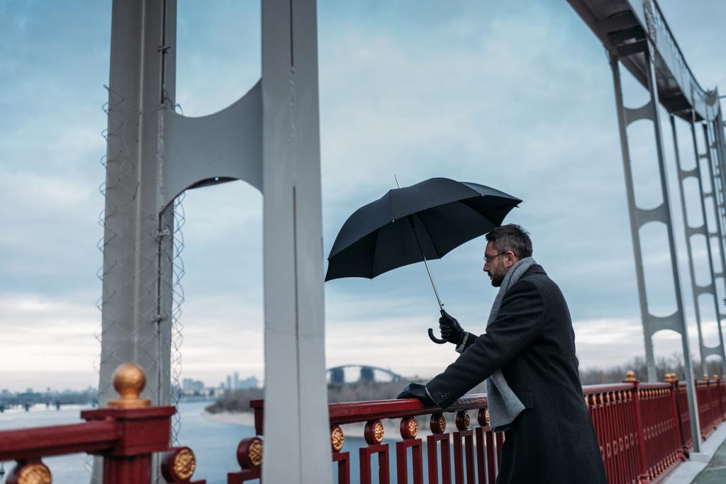 handsome lonely man with umbrella standing on bridge - Photo, Image