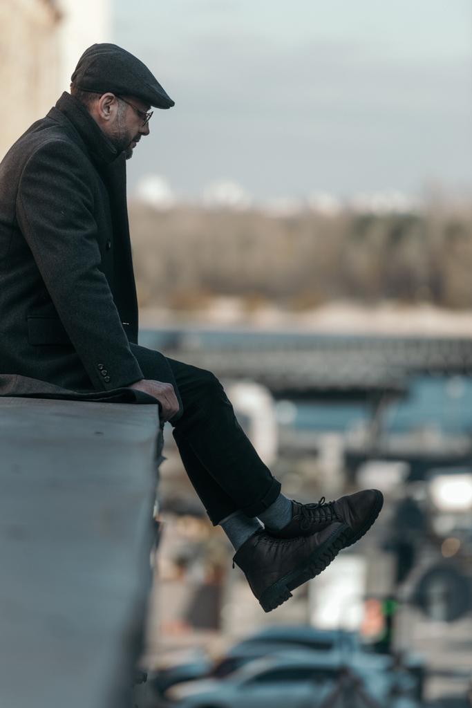 μοναχικό μέσης ηλικίας άνθρωπο κάθεται στην οροφή του κτιρίου - Φωτογραφία, εικόνα
