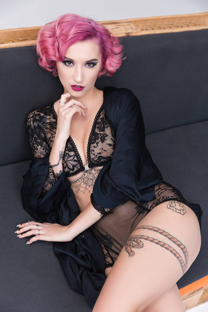 seductora chica de pelo rosa tatuada en lencería transparente posando en el sofá
  - Foto, imagen