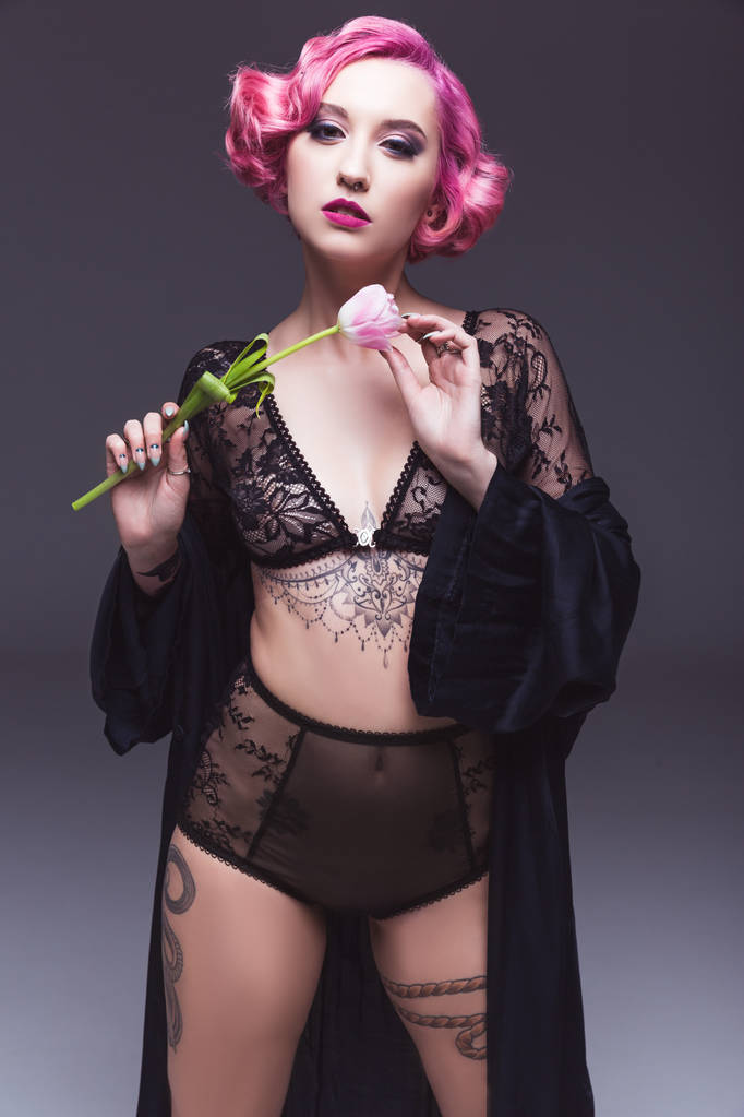 seductora chica tatuada en lencería transparente con flor delante de fondo gris
 - Foto, imagen