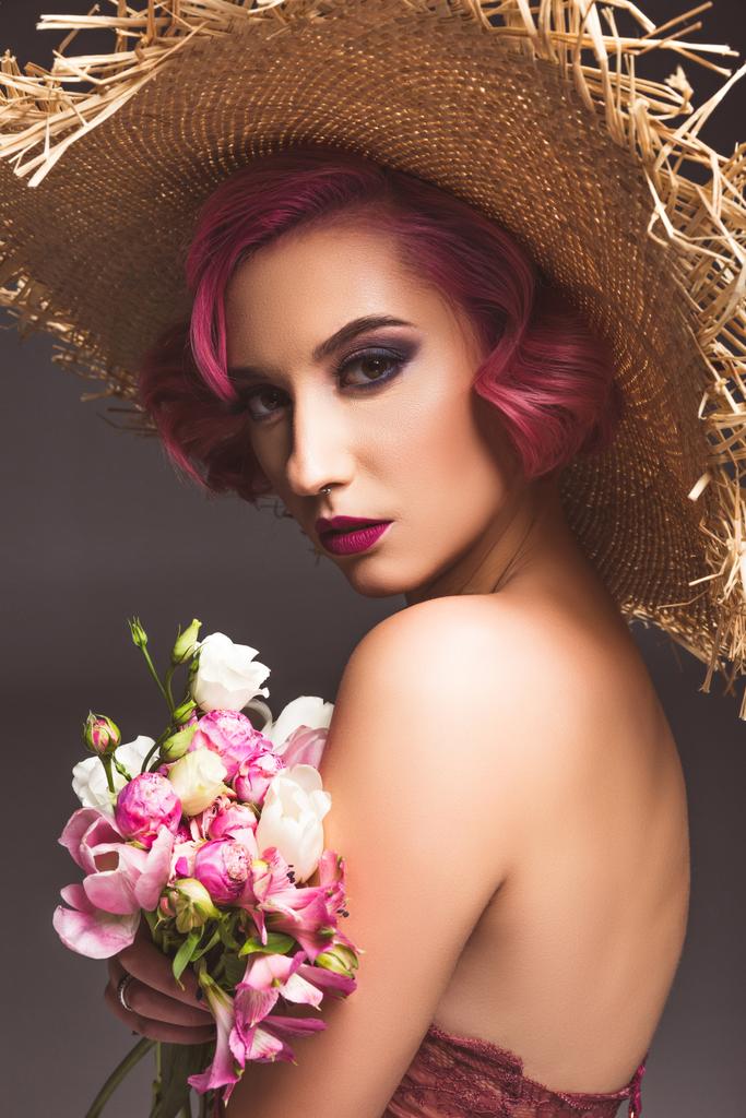 pretty pink haired girl in straw hat posing with flowers infront of grey background  - Photo, Image