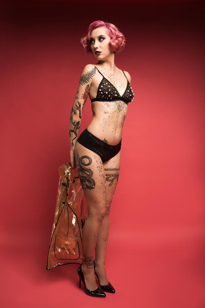 houkutteleva pin up tyttö tatuoinnit alusvaatteita tilalla sadetakki infront punaista taustaa
 - Valokuva, kuva