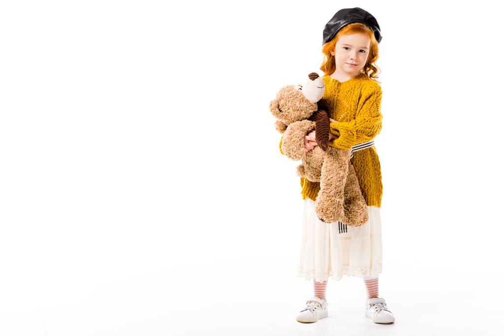 niño de pelo rojo de pie con oso de peluche aislado en blanco
    - Foto, Imagen