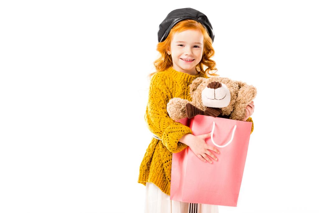 rood haar kind houden teddybeer in boodschappentas geïsoleerd op wit - Foto, afbeelding