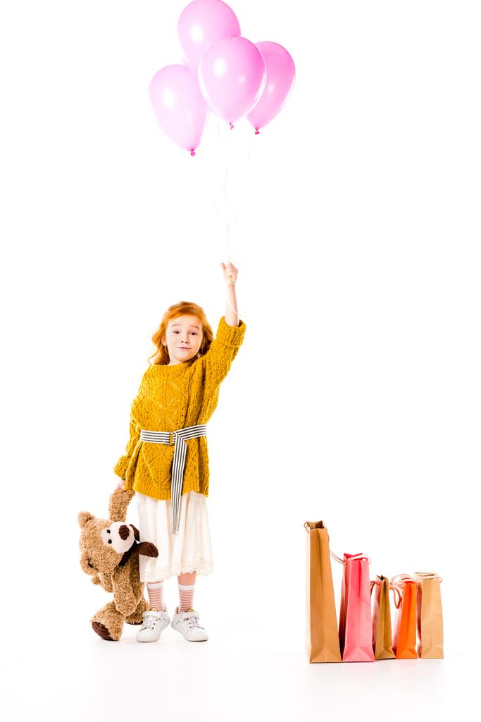 red hair child holding bundle of balloons and teddy bear in hands isolated on white - Photo, Image