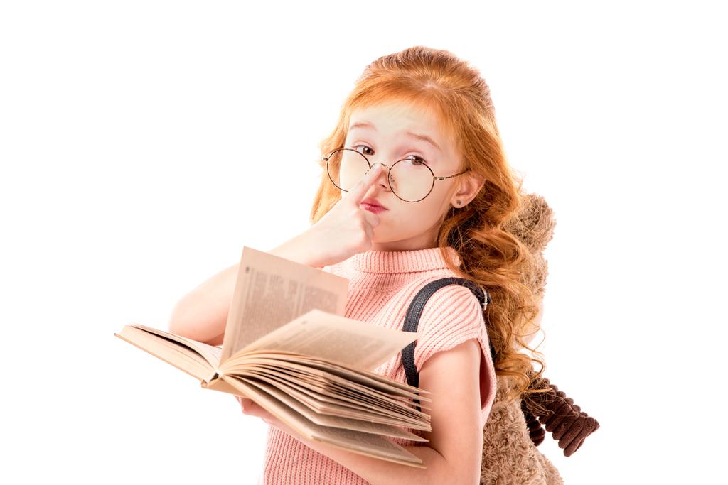 reflexivo pelo rojo niño sosteniendo libro aislado en blanco
 - Foto, Imagen