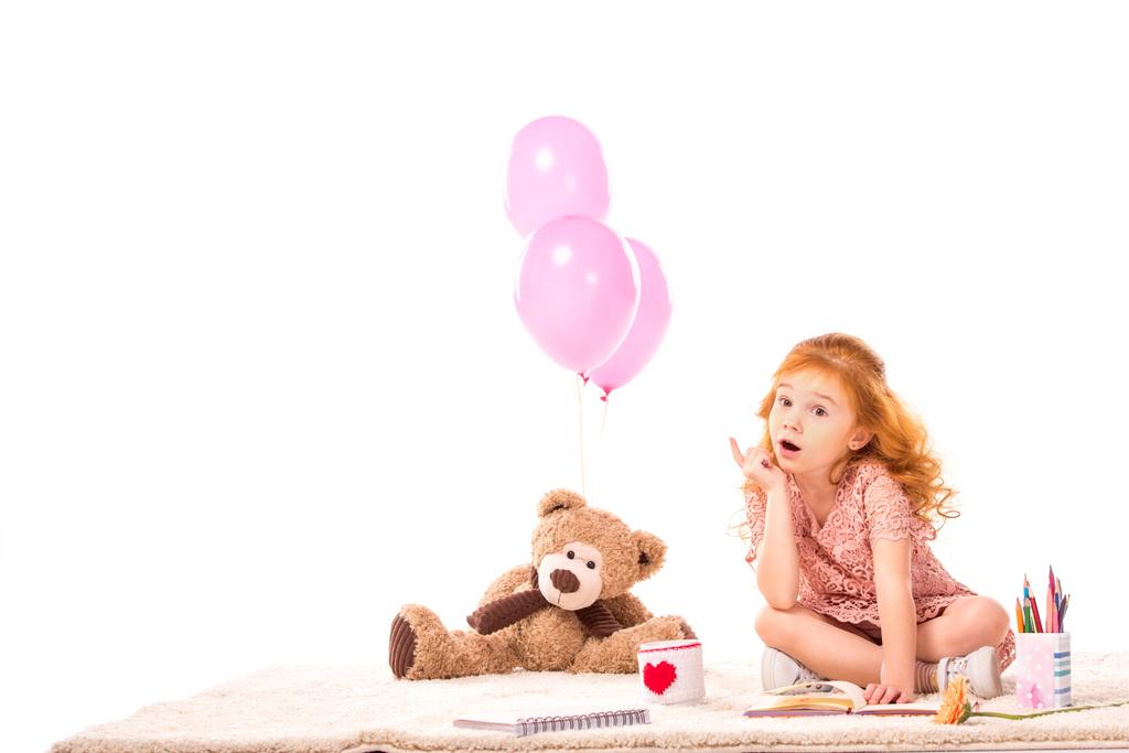 überrascht rotes Haar Kind sitzt mit Spielzeug auf Teppich isoliert auf weiß - Foto, Bild