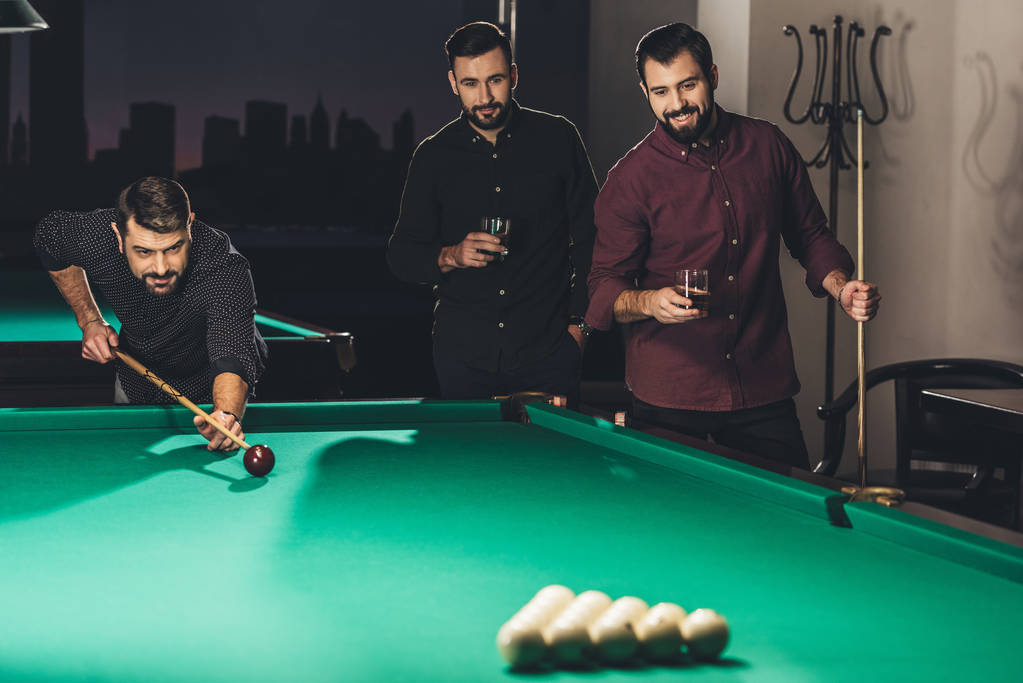successful handsome man playing in pool at bar with friends - Photo, Image