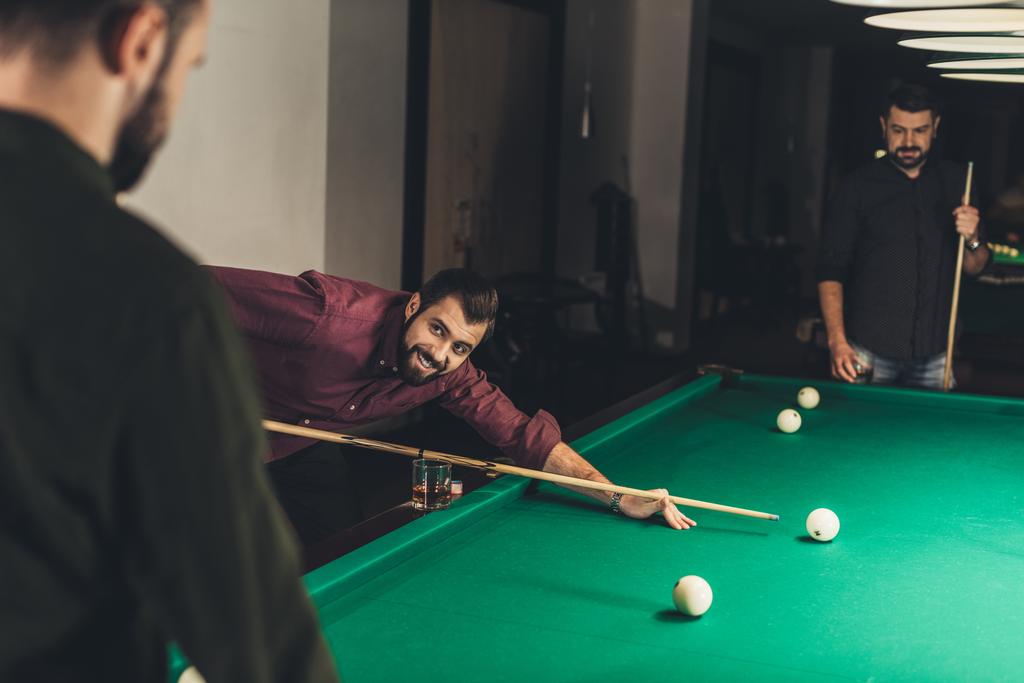company of handsome men playing in pool at bar - Photo, Image